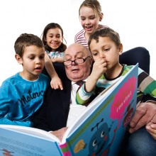 Äldre man läser bok för yngre barn